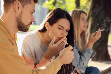 People smoking cigarettes outdoors on sunny day