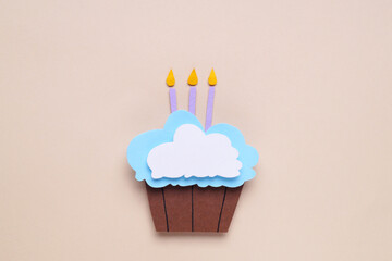 Birthday party. Paper cupcake with candles on beige background, top view