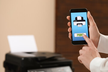 Man using printer management application on mobile phone indoors, closeup and space for text