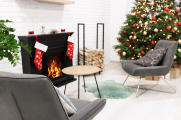Beautiful Christmas tree near fireplace and cosy armchairs in room. Interior design