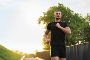 Attractive sporty man in fitness clothes jogging outdoors