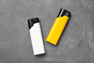 Stylish small pocket lighters on grey table, flat lay