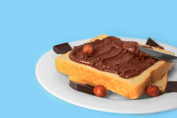 Spreading chocolate paste onto bread on light blue background, closeup. Space for text