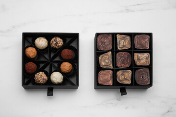 Boxes of tasty chocolate candies on white marble table, flat lay