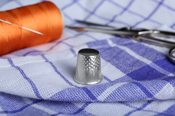 Silver thimble on checkered fabric. Sewing accessories