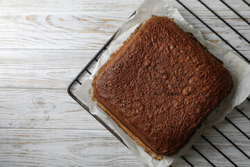 Homemade chocolate sponge cake on white wooden table, top view. Space for text