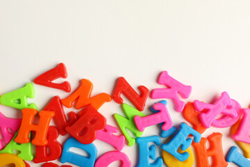 Naklejka premium Many colorful magnetic letters on white background, flat lay. Space for text