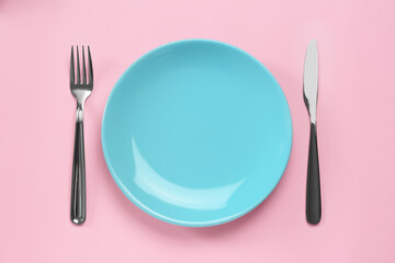 Clean plate and shiny silver cutlery on pink background, flat lay