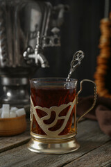 Glass of tea in vintage holder and samovar on wooden table