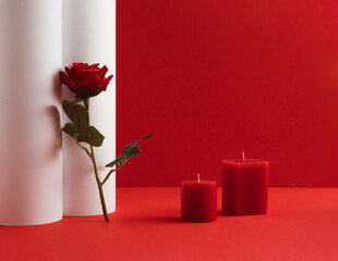 Romantic composition with candles and red rose flower on red and white background. Valentines Day idea. Copy space.