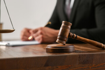Law and justice. Closeup of judge working at wooden table, focus on gavel