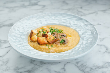 Delicious cream soup with mushrooms and croutons on white marble table