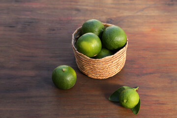 Fresh ripe limes in wicker basket on wooden table