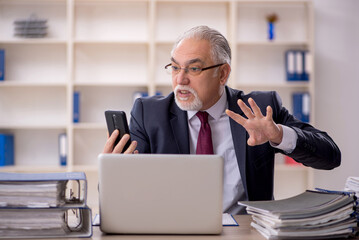 Old male employee sitting at workplace