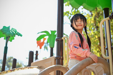 Pretty Asian girl playing on playground equipment