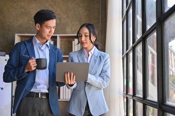 Professional Asian businessman talking and giving his advice to a female colleague.