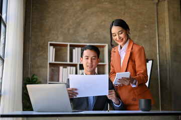 Two Asian financial analysts working on sales and financial investment report together