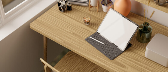 Obraz premium Top view of a minimal and cozy workspace with tablet mockup with wireless keyboard and decor