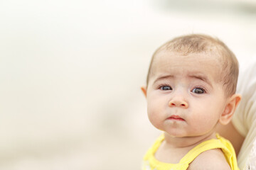 Infant baby portrait with bright eyes eyelashes isolated with shallow depth of field against light colored background