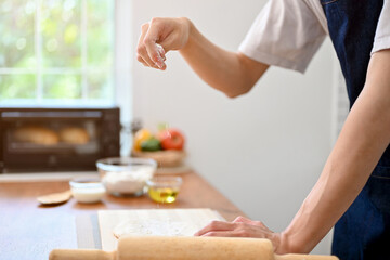 Obraz na płótnie Canvas Close-up image, A male baker making dough on the kitchen table, preparing raw dough