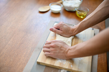 Close-up hand image of a male baker kneading raw dough, preparing dough for his pastry