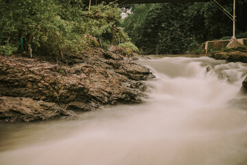 picture of a river with swift water flow and pillow lava  rocks in Yogyakarta, Indonesia, long exposure shot, no people