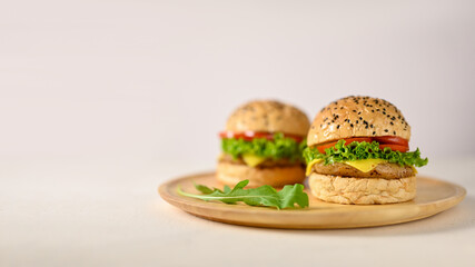 Tasty delicious beef burgers on wooden plate on white background with empty space.