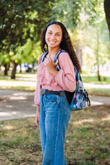Smiling young latin student woman standing in the park. Determination. Centennial generation