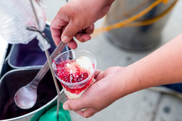 A vendor prepares strawberry taho, a popular delicacy in Baguio. Strawberry Taho, a popular delicacy in Baguio. A soybean curd with strawberry sauce and pieces.