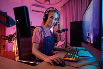 Cheerful teenage girl streaming herself playing first person shooter