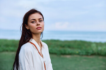 Beauty portrait of a woman with wet hair in a white shirt near the leaves of a tropical tree, beauty and health tanned skin, the concept of facial skin care and hair health on vacation