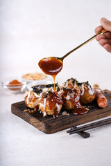 Takoyaki is Japanese Street Food containing with octopus, sausage or cheese. garnish with seaweed and katsuobushi
