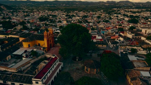 iglesia amarilla con un parque vac&iacute;o, junto a un arbol con mas de 90 a&ntilde;os de edad dentro la ciudad 