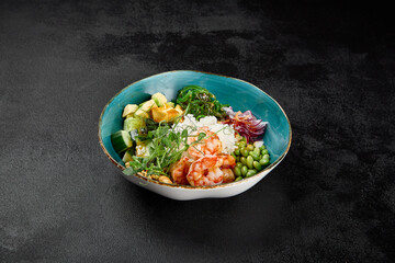 Poke bowl with shrimps and vegetables on black concrete background. Ahi poke with shrimp, rice, edamame and unagi sauce. Prawns poke bowl in minimal style on black background. Salad bowl with prawn.