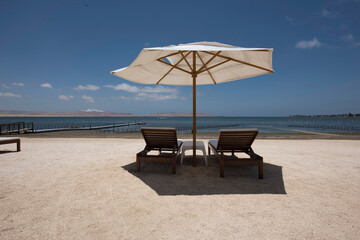 tropical white sand beaches with umbrellas and wooden chairs in pacific ocean paracas bay in luxury...