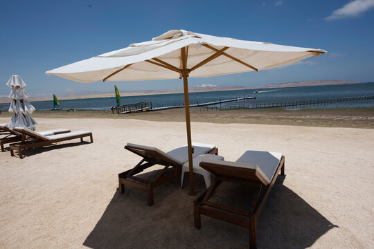tropical white sand beaches with umbrellas and wooden chairs in pacific ocean paracas bay in luxury hotels peru, june 2020