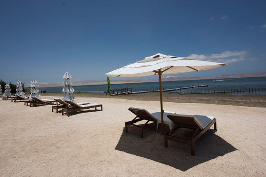 tropical white sand beaches with umbrellas and wooden chairs in pacific ocean paracas bay in luxury hotels peru, june 2020