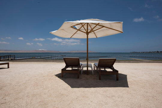 tropical white sand beaches with umbrellas and wooden chairs in pacific ocean paracas bay in luxury hotels peru, june 2020