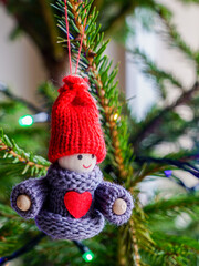 A small smiling wooden doll boy with a red knitted hat and a red heart on his chest