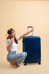 Young attractive Asian woman traveler wearing sunglasses with luggage, passport and boarding pass ticket isolated on yellow background, Tourist girl having cheerful holiday trip concept