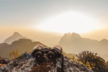 binoculars on top of rock mountain at sunset