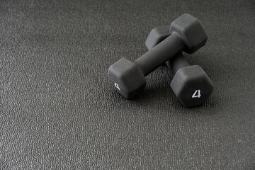 Pair of small hand weights on a black gym floor
