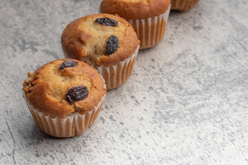 Banana cupcakes sprinkled with raisins. Copy space on gray background.