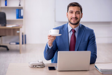 Fototapeta na wymiar Young male employee drinking coffee in the office
