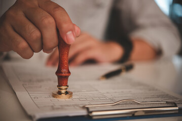 businessman hand stamping approved on certificate document contract in office. Lawyer stamping permit on paperwork at wooden desk.