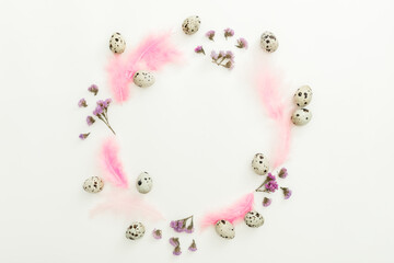 Round composition with easter eggs, flowers and feathers on white background. Flat lay, top view
