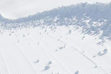 Fototapeta na wymiar Long curved edge of winter snow on groomed ski slope background