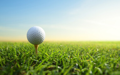Golf ball on tee with sunrise  background.