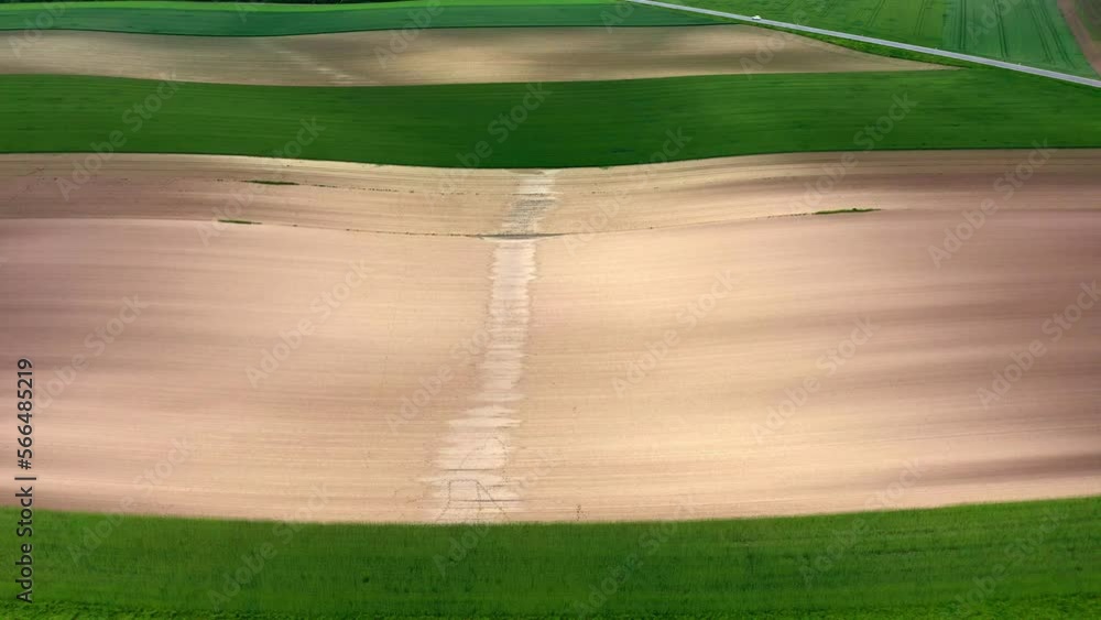 Poster emergence of a hollow path between an empty plowed field in daytime. - aerial