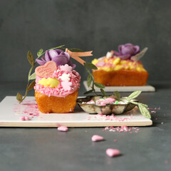 kleine sommerliche Zitronenkuchen mit Frischkäse Topping und bunter Dekoration - 566486295
